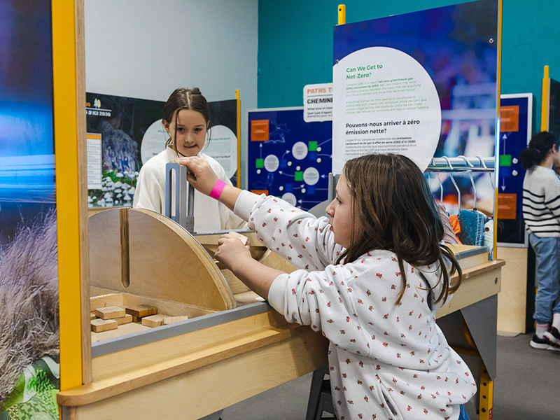 two young girls learning about achieving net-zero emissions at an interactive display