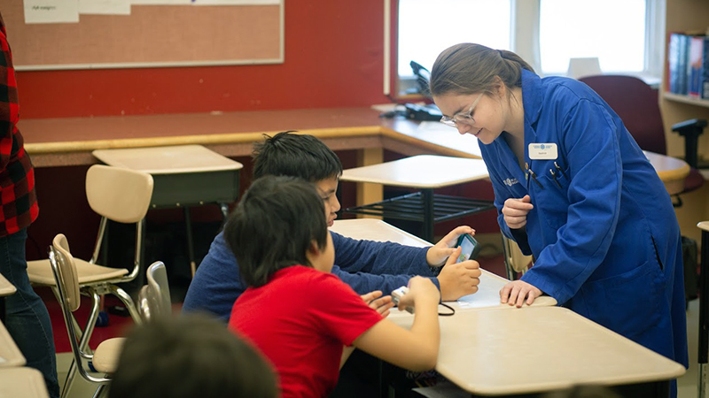 example of an outreach school program — bluecoat in the classroom speaking to two students at their desk